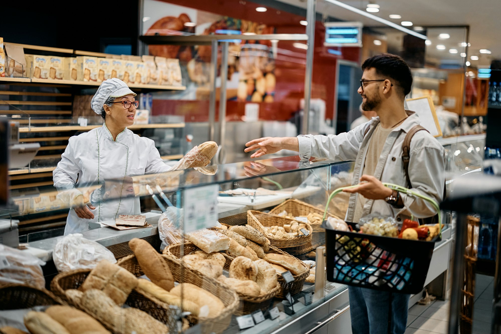 Supermarket baker serving her customer in supermarket bakery.